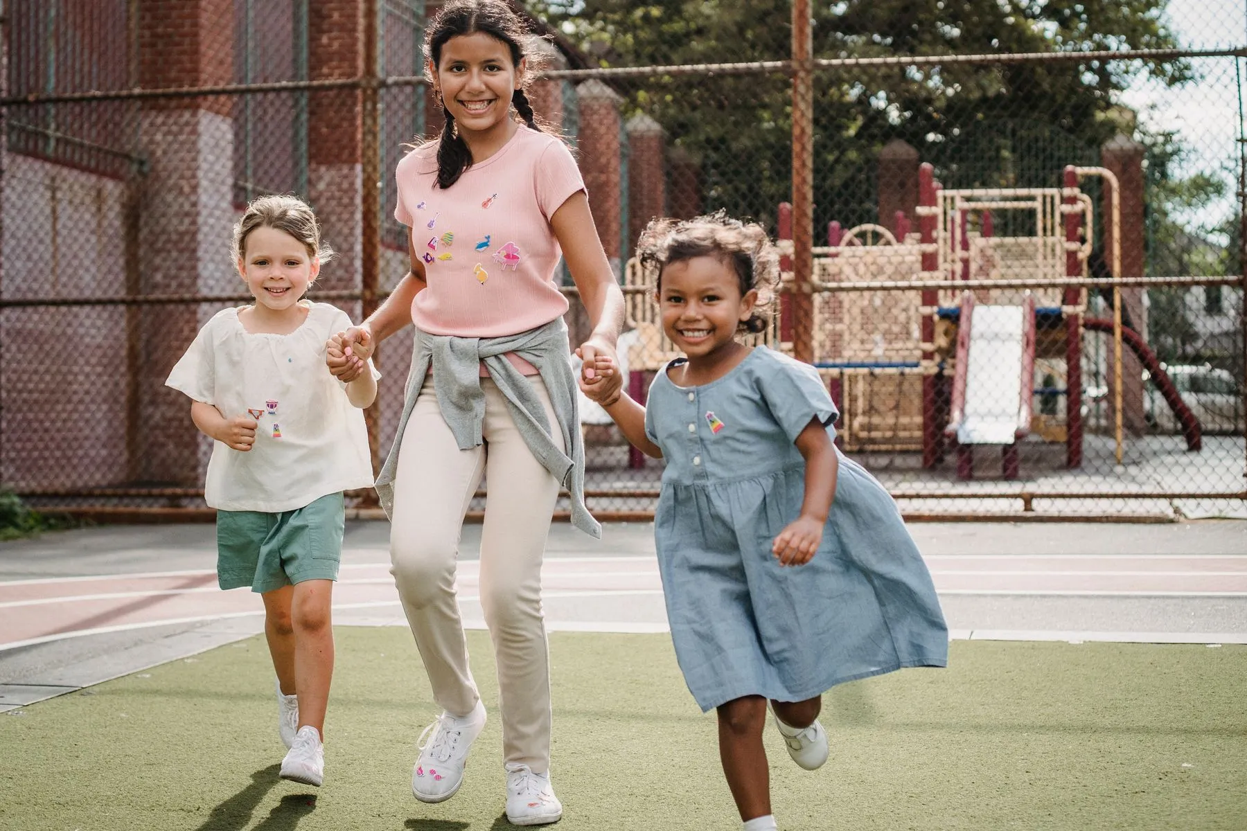 Children running and playing outdoors with an adult