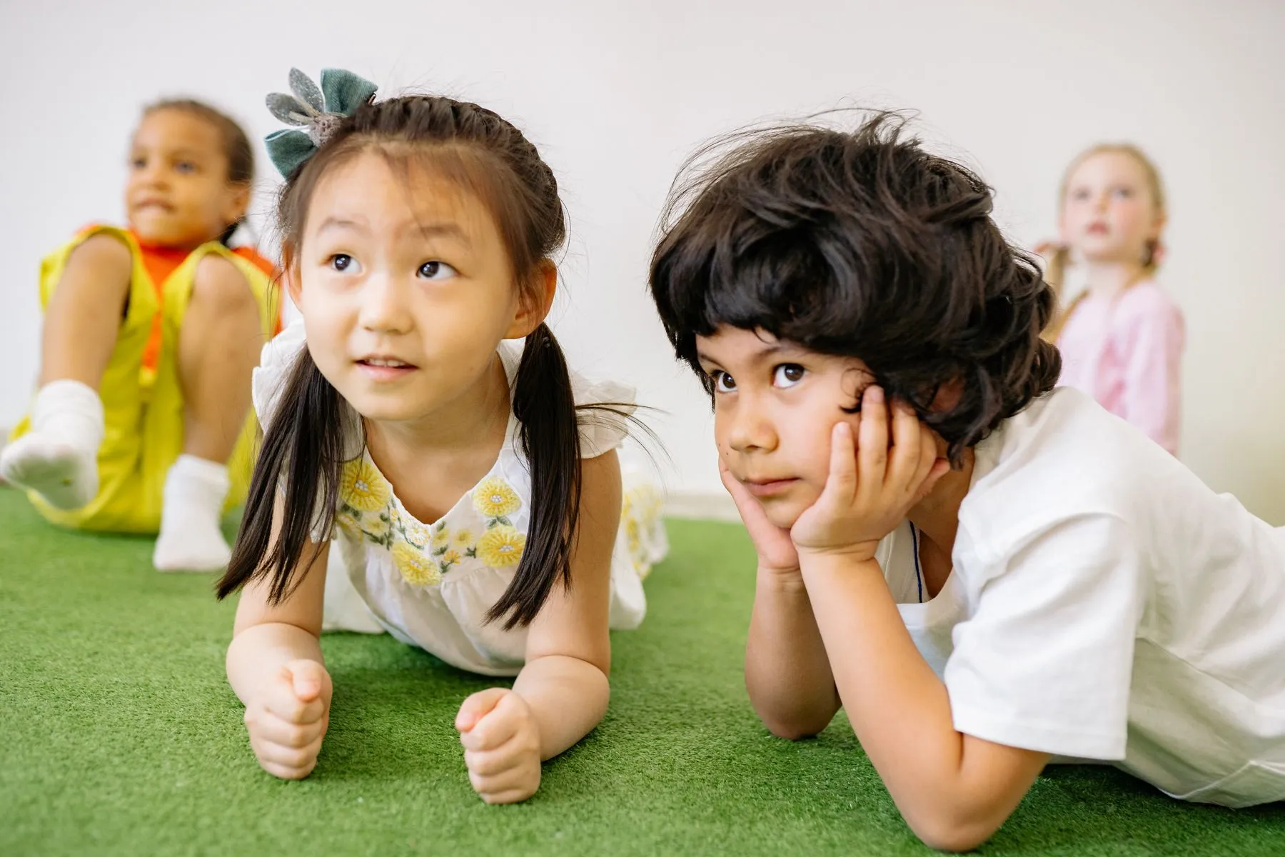 Young children resting quietly on a soft floor mat indoors