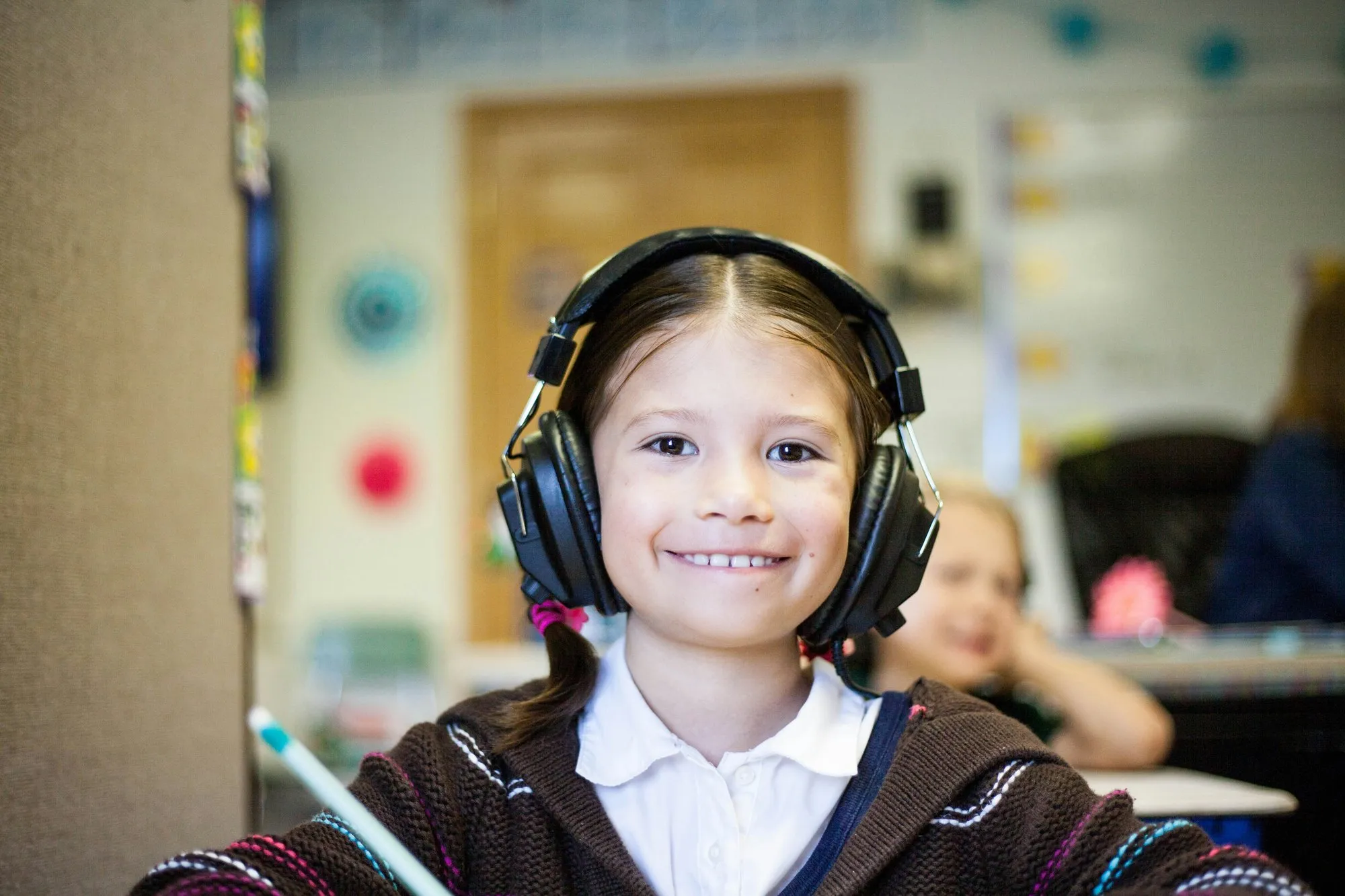A child smiling during listening time, wearing headphones